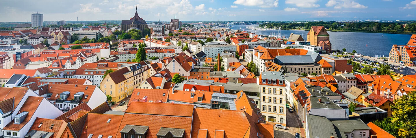 Zu sehen ist ein Panorama Bild der Skyline von Rostock bei sonnigem Wetter.