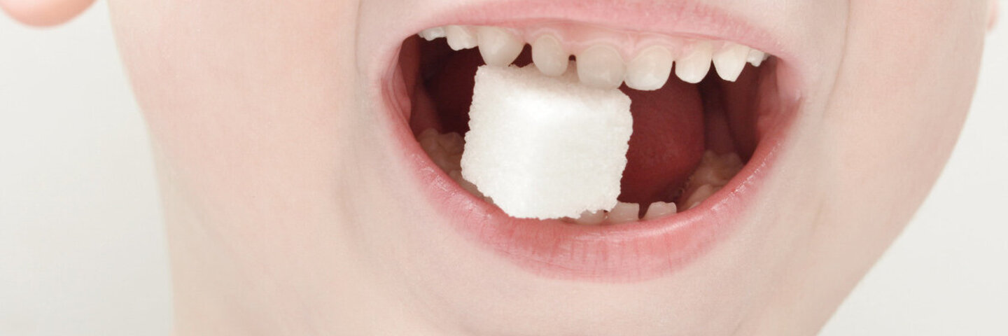 Kleiner Junge mit Würfelzucker im Mund - wieviel Zucker am Tag ist ok?