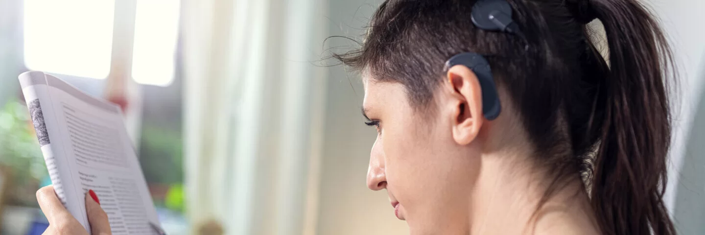 Eine Frau trägt ein Cochlea-Implantat. Damit nimmt sie trotz ihres Hörschadens Sprache und Geräusche wieder gut wahr.