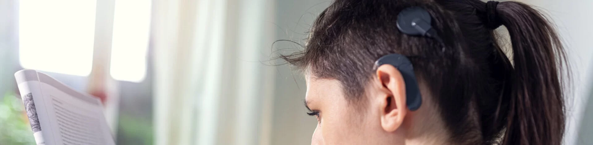 Eine Frau trägt ein Cochlea-Implantat. Damit nimmt sie trotz ihres Hörschadens Sprache und Geräusche wieder gut wahr.