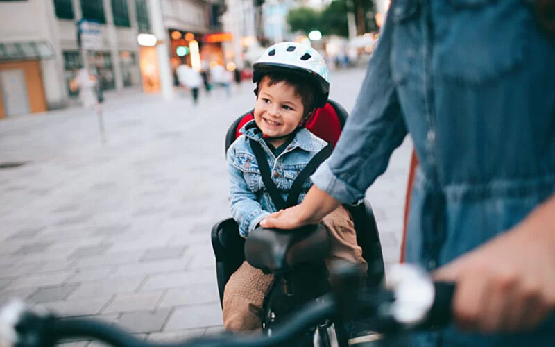 Ein Kind sitzt im Kindersitz auf dem Fahrrad.