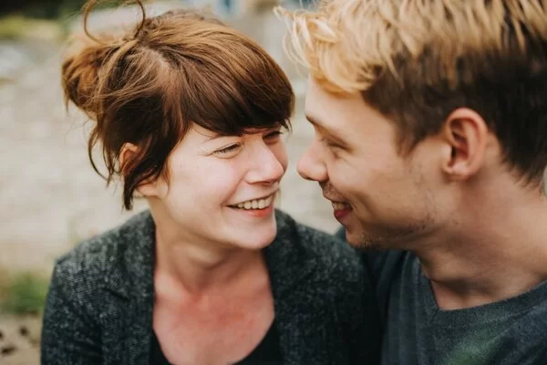 Eine junge Frau und ein junger Mann gucken sich in die Augen und lächeln.
