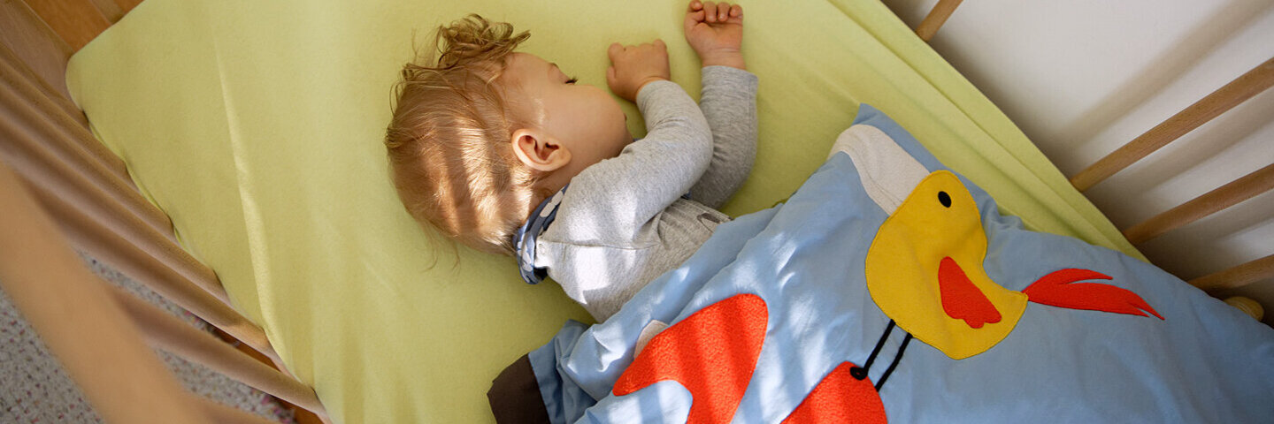 Säugling liegt im Babybett und schläft