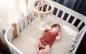 Säugling liegt im Babybett und schläft.