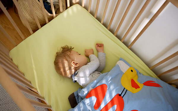 Säugling liegt im Babybett und schläft