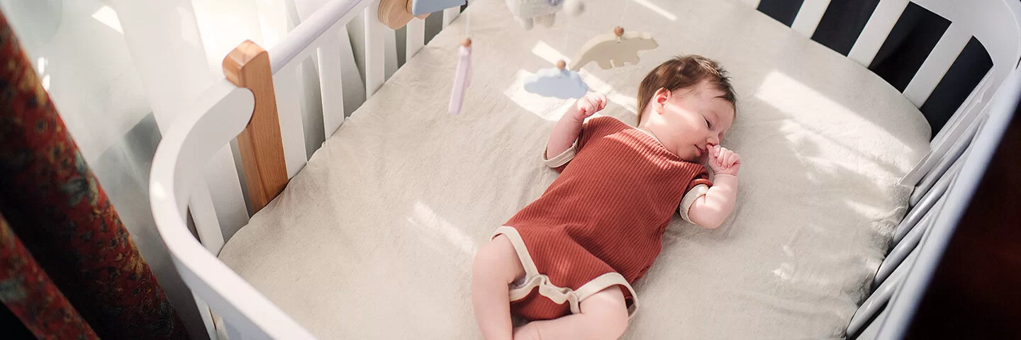 Säugling liegt im Babybett und schläft.