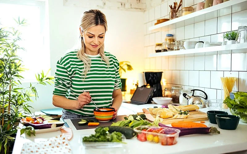Eine Frau bereitet in der Küche aus Gemüse eine gesunde Mahlzeit zu.
