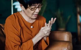 Frau massiert ihre schmerzende Hand, sie leidet unter rheumatoider Arthritis.