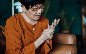 Frau massiert ihre schmerzende Hand, sie leidet unter rheumatoider Arthritis.