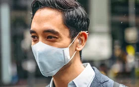 Geschäftsmann trägt Verschmutzungsmaske in der Stadt