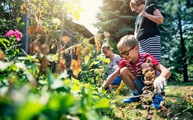 : Kinder helfen bei der Gartenarbeit und lernen dabei etwas über giftige Pflanzen.