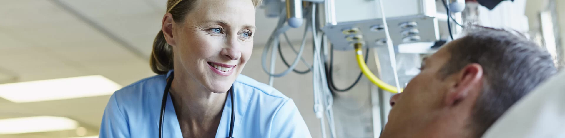 Smiling doctor looking at patient in hospital ward.