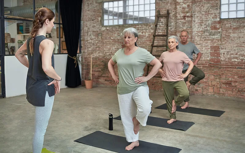 Eine Gruppe älterer Menschen geht zum Sturzpräventionstraining in einen Sportkurs.