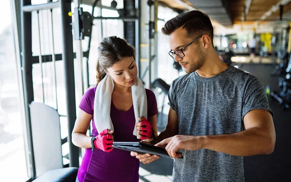 Eine Sportlerin und ihr Trainer besprechen einen Trainingsplan, der die leistungssteigernden Effekte der Superkompensation nutzt.