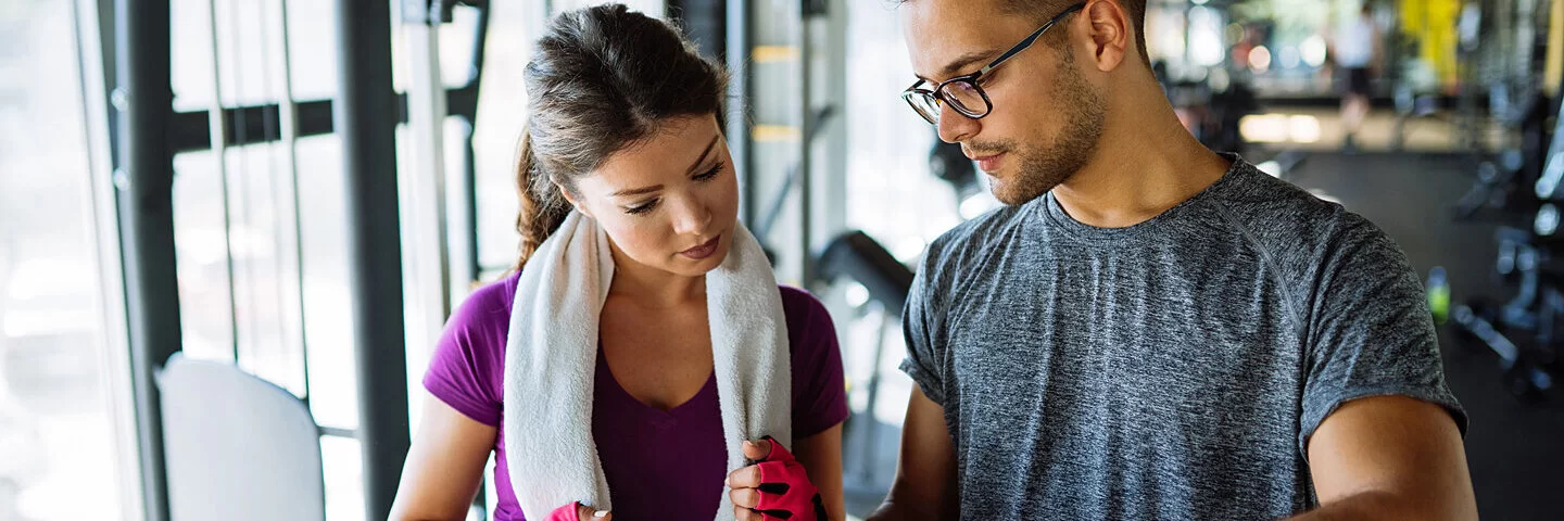 Eine Sportlerin und ihr Trainer besprechen einen Trainingsplan, der die leistungssteigernden Effekte der Superkompensation nutzt.