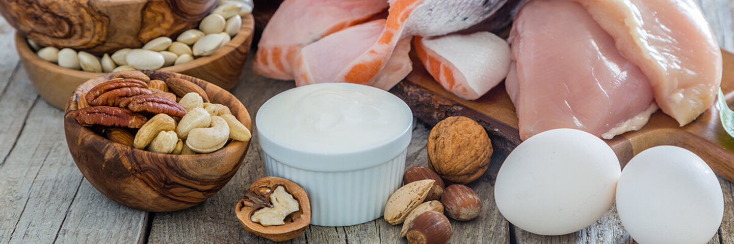 Nüsse, Geflügel, Ei und Fisch auf Holztisch angerichtet.