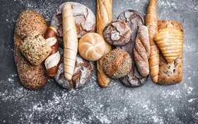 Auf einem Tisch liegen unterschiedliche Brotlaibe, Brötchen und andere Backwaren.