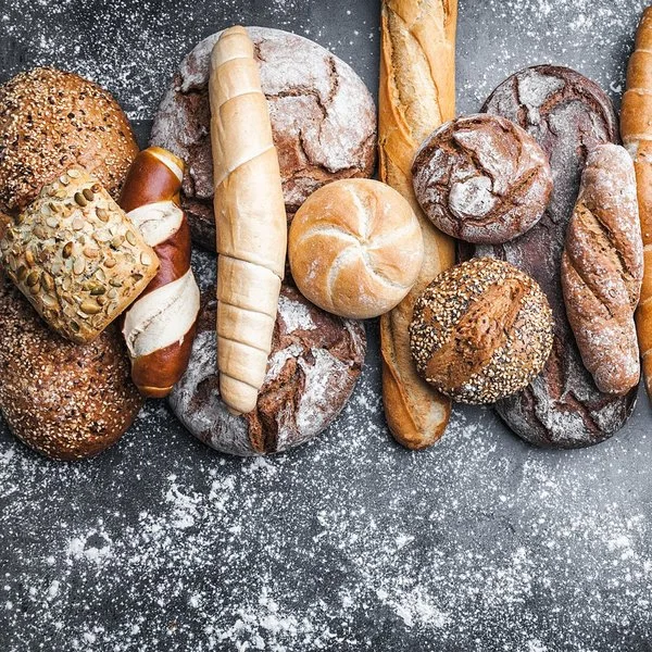 Auf einem Tisch liegen unterschiedliche Brotlaibe, Brötchen und andere Backwaren.