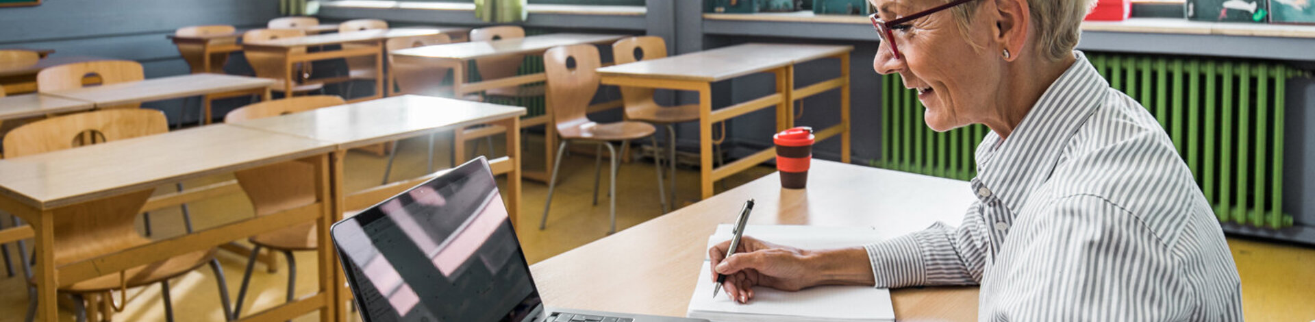 Eine Frau arbeitet mit ihrem Laptop im Klassenzimmer. Sie meldet sich für den Henrietta-Live-Webcast an.