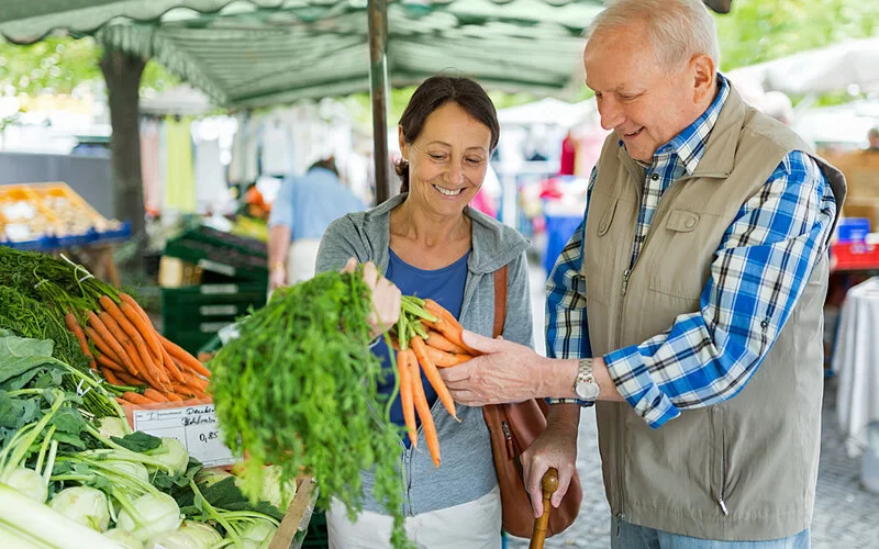 Ehepaar kauft Möhren auf dem Markt, weil sie laut Kalorientabelle nur wenig Kalorien haben.