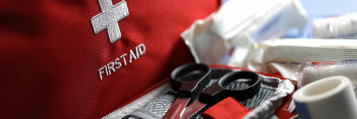 Diverse medizinische Hilfsprodukte liegen verwendungsbereit in einer roten Erste-Hilfe-Tasche.