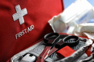 Diverse medizinische Hilfsprodukte liegen verwendungsbereit in einer roten Erste-Hilfe-Tasche.