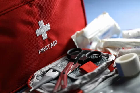 Diverse medizinische Hilfsprodukte liegen verwendungsbereit in einer roten Erste-Hilfe-Tasche.