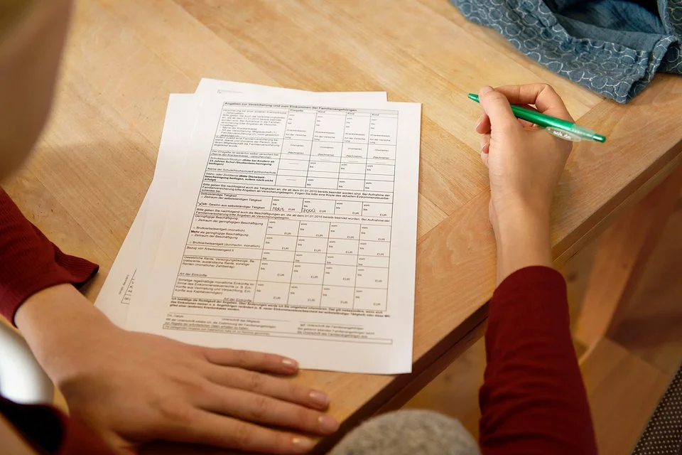 Eine Frau sitzt an einem Tisch mit mehreren Zetteln vor sich. In der Hand hält sie einen Stift. Die AOK stellt alle wichtigen Leistungsanträge und Formulare zusammen.
