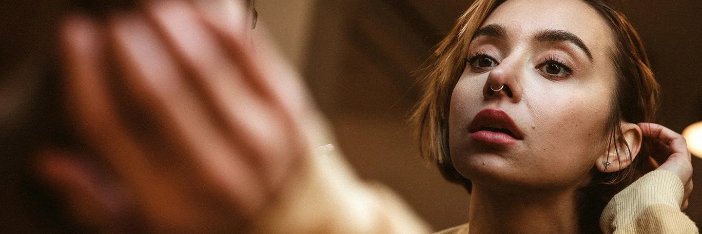 Eine Frau betrachtet ihr Nasen-Piercing im Spiegel.