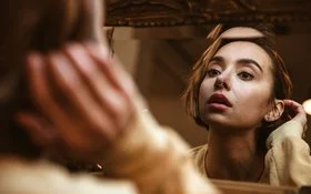 Eine Frau betrachtet ihr Nasen-Piercing im Spiegel.