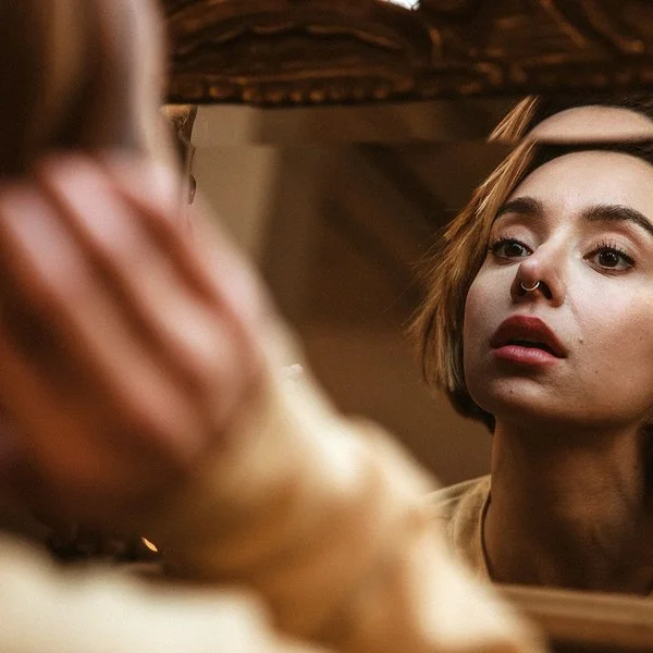 Eine Frau betrachtet ihr Nasen-Piercing im Spiegel.