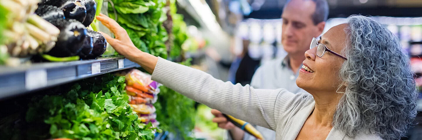 Älteres Ehepaar kauft gemeinsam frisches Gemüse in einem Supermarkt.