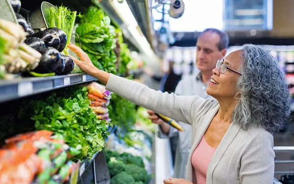 Älteres Ehepaar kauft gemeinsam frisches Gemüse in einem Supermarkt.