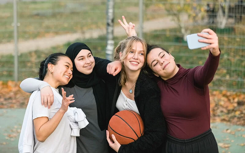 Jugendliche machen zusammen ein Selfie. In der Adoleszenz sind Gleichaltrige für Jugendliche wichtig.