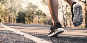 Es sind die Füße eine Frau in Sportschuhen zu sehen, die auf einer Straße steht.