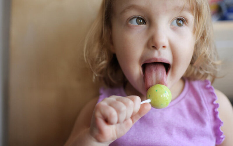 Kleines Mädchen mit Lolli im Mund - wieviel Zucker am Tag ist ok?