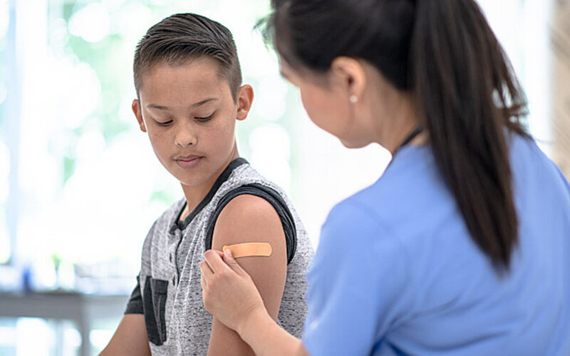Ein Junge bekommt von einer Ärztin eine Impfung verabreicht.