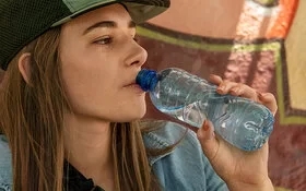 Frau trinkt Wasser aus einer Plastikflasche, dabei kann Mikroplastik in den Körper gelangen.