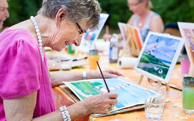 Eine Seniorin zeichnet in einem Kurs gemeinsam mit anderen Personen.