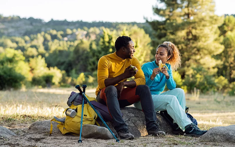 Ein wanderndes Paar macht eine Pause und stärkt sich mit Banane und Apfel.