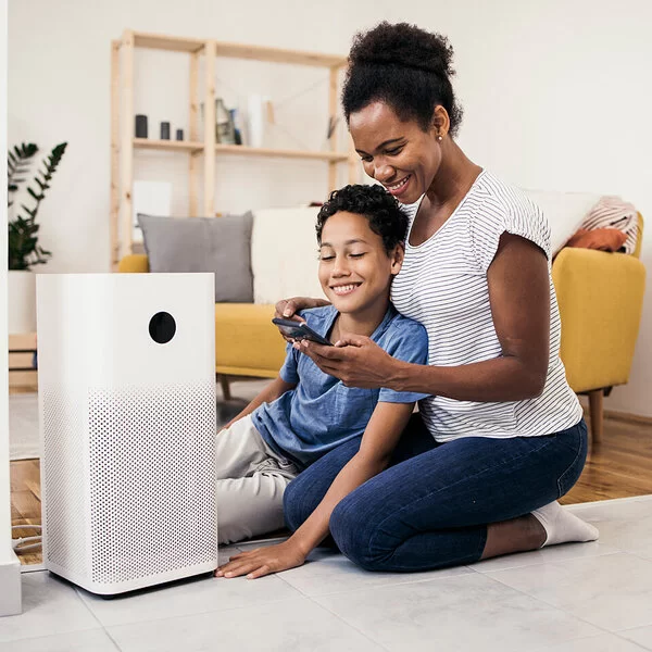 Mutter und Sohn stellen ihren Luftfilter im Wohnzimmer richtig ein.