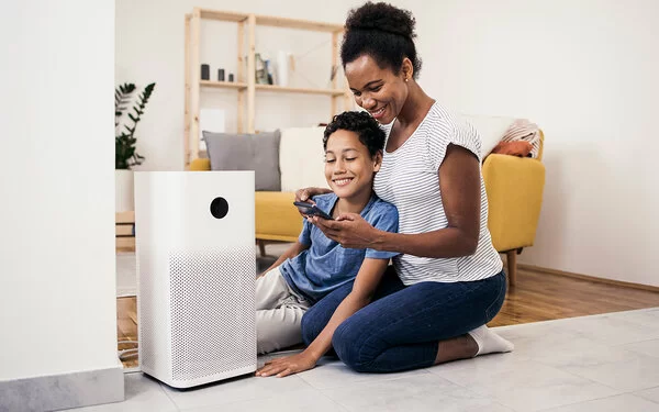 Mutter und Sohn stellen ihren Luftfilter im Wohnzimmer richtig ein.