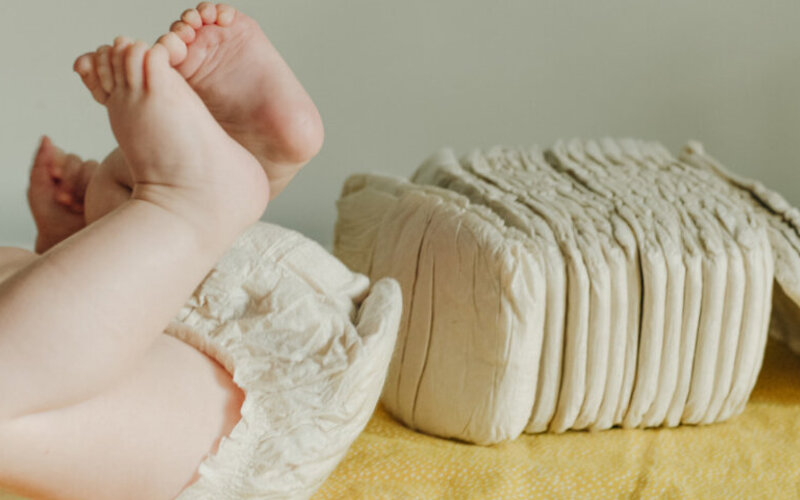 Baby liegt auf einer Wickelkommode und wurde mit Ökowindeln gewickelt.