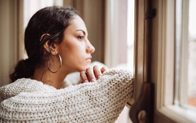 Eine Frau schaut nachdenklich aus dem Fenster.