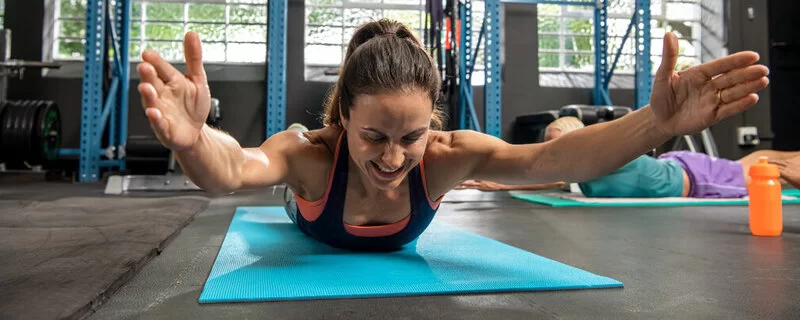 Frau macht Planks auf einer Bodenmatte im Fitnessstudio.