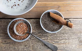 Chia- und Leinsamen in Schalen auf einem Tisch.