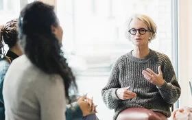 Ältere Frau spricht während der Teilnahme an einer Patientenschulung für chronische Erkrankungen.