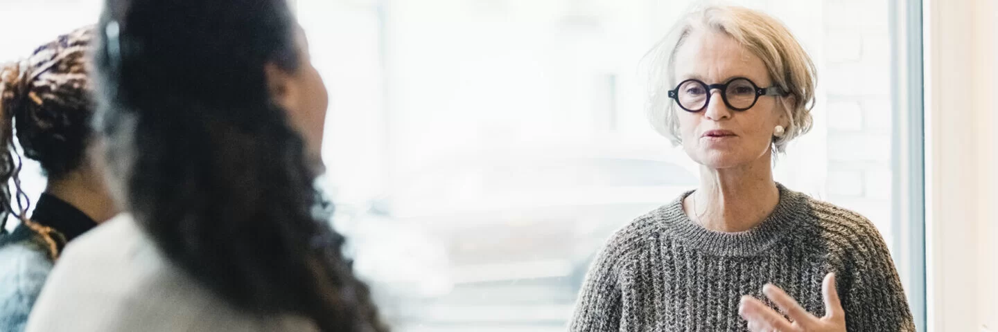 Ältere Frau spricht während der Teilnahme an einer Patientenschulung für chronische Erkrankungen.