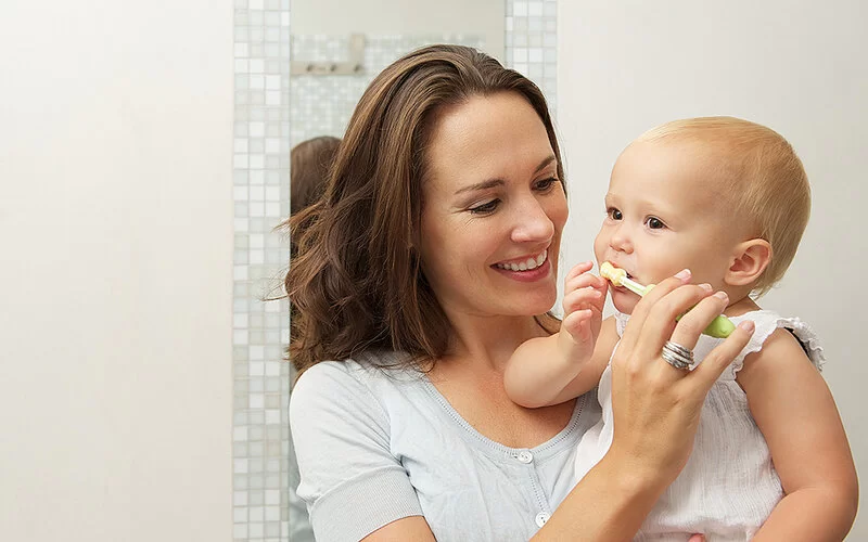 Eine Mutter putzt die Zähne ihres Babys.