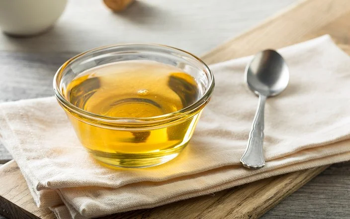 Auf einem hölzernen Untergrund liegt eine Serviette. Darauf steht eine kleine Schüssel mit Agavendicksaft.